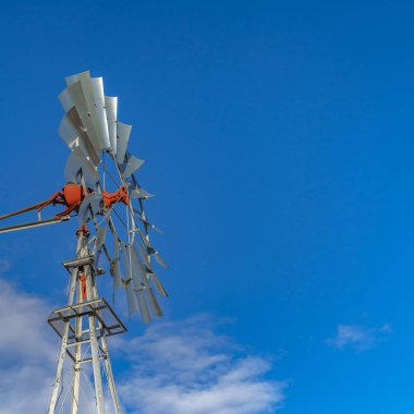 Clear Square Arka planda canlı mavi gökyüzü ve kabarık bulutlar ile bir windpump kapatın