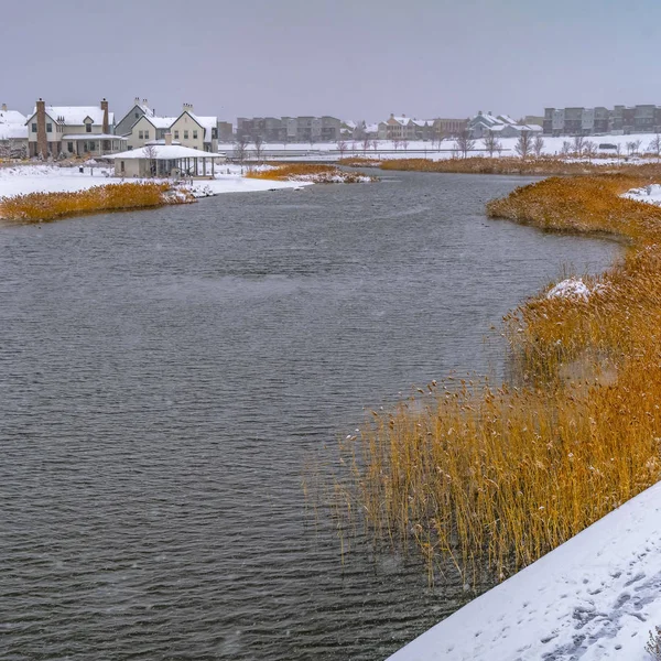 Clear Square Casas cerca de un lago con nieve y orillas cubiertas de hierba — Foto de Stock