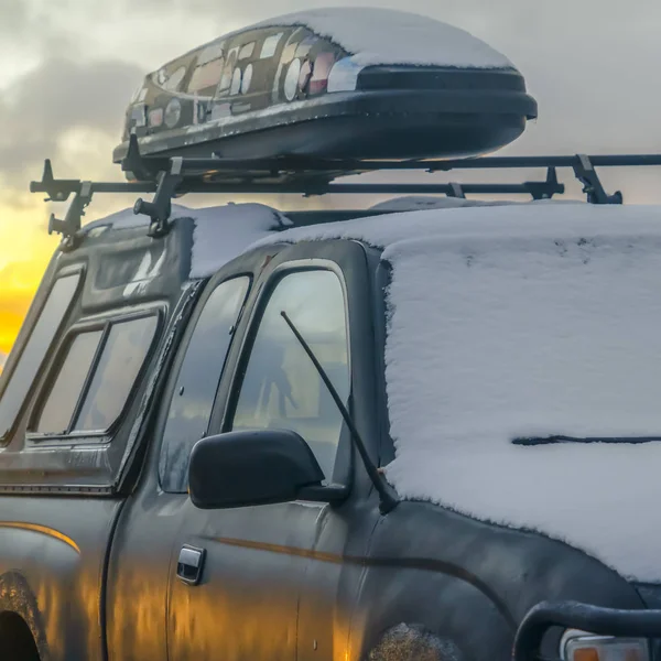 Neve coberto veículo preto com um carro transportador superior montado no rack do telhado — Fotografia de Stock