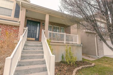 Beyaz korkuluklar ile beton merdivenler bir evin ön verandaya gidiyor