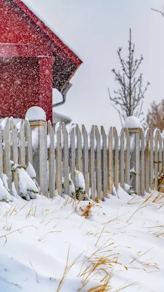 Прозорий вертикальний зимовий пейзаж з яскравими червоними будинку і снігу перевищила Пікет паркан на світанку — стокове фото