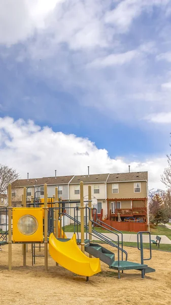 Clear Colorful slides at a playground with homes and cloudy sky in the background