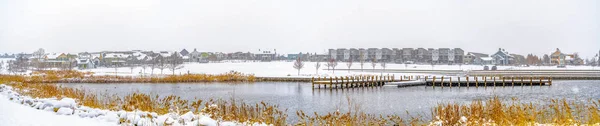 Panorama of a lake in Daybreak Utah with wooden decks and snowy shore in winter