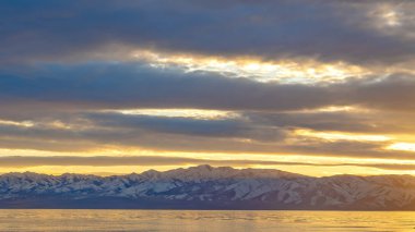 Çarpıcı bir bulutlu gökyüzü altında bir göl ve karla kaplı dağ Panorama Manzara panorama