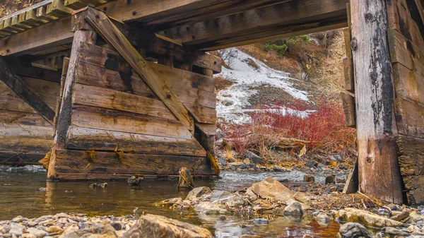 Panorama frame Ponte de madeira rústica atravessando um riacho rochoso — Fotografia de Stock