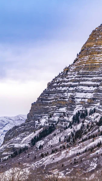 Impresionante montaña vertical con árboles dispersos y nieve fresca o — Foto de Stock