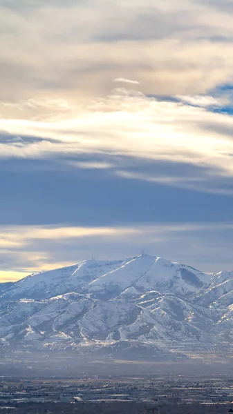 Verticale opvallende zonovergoten berg bedekt met sneeuw onder een levendige — Stockfoto