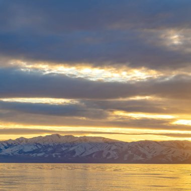 Bir gölün Kare Manzara panoraması ve altında karla kaplı dağ 