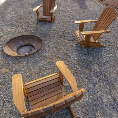 Kare çerçeve Güneşli bir günde bir parkta bir yangın çukuru etrafında Kahverengi ahşap sandalyeler