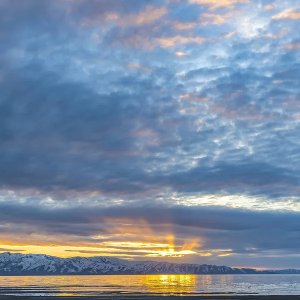 Plac jezioro i śnieg ograniczona Góra pod niebo wypełnione chmurami o zachodzie słońca — Zdjęcie stockowe