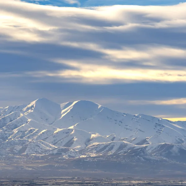 Τετράγωνη κορνίζα εντυπωσιακό ηλιόλουστο βουνό επικαλυμμένα με χιόνι κάτω από ένα ζωηρό γαλάζιο ουρανό με σύννεφα — Φωτογραφία Αρχείου