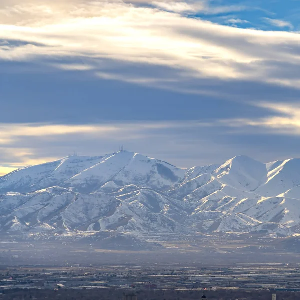 Carré Montagne ensoleillée recouverte de neige sous un ciel bleu vif avec des nuages — Photo