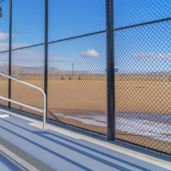 Marco cuadrado Las gradas iluminadas por el sol con vistas a un vasto campo de deportes en el otro lado de la cerca — Foto de Stock