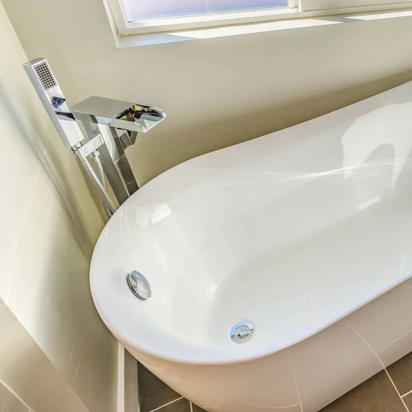 Interior del baño cuadrado con una bañera reluciente contra la pared blanca y el suelo gris —  Fotos de Stock
