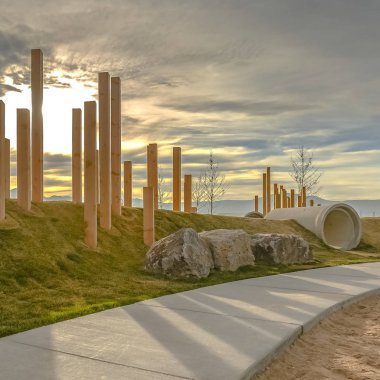 Güneşli bir günde kumlu ve çimenli bir arazide çalışan Kare Asfalt yol