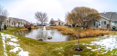 Karla kaplı çimlerle çevrili merkezinde çeşmeli küçük gölet