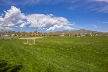Dağ ve bulutlu manzaralı futbol sahası ve beyzbol sahası