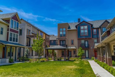 Veranda parlak mavi gökyüzü havai ile townhouses çevrili bir çim üzerinde