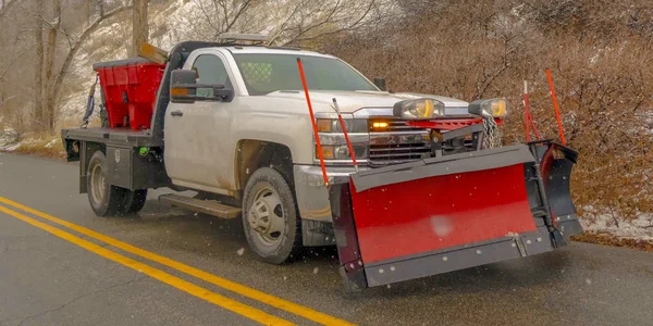 Camioneta blanca que viaja por una carretera a lo largo de una montaña nevada i — Foto de Stock