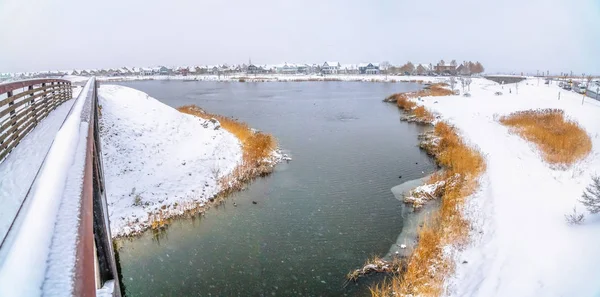 Puente nevado con vistas a un tranquilo lago plateado en medio de unas tierras heladas — Foto de Stock