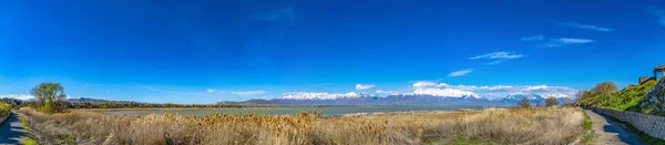 Panorama de trilhas e gramíneas marrons em torno de um lago visto o — Fotografia de Stock