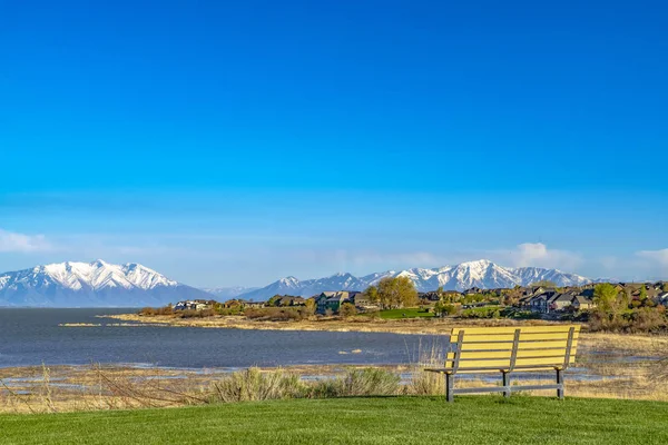 Banco en un campo cubierto de hierba con vistas al lago y la montaña nevada agai —  Fotos de Stock