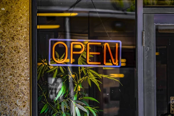 Ticari bir binanın cam duvarında asılı neon açık bir tabelanın yakın çekim — Stok fotoğraf