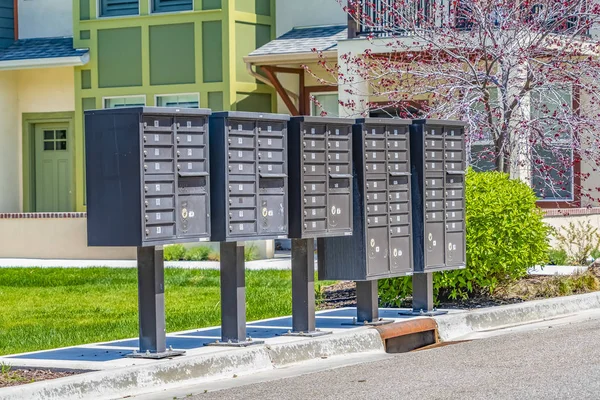 Řada poštovních schránek s očíslovanými jednotkami na sluncem osvětlovaném chodníku — Stock fotografie