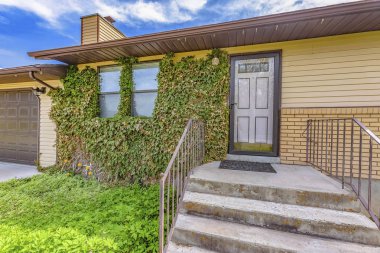 Mavi gökyüzüne karşı garaj kapısı ve ön kapı manzaralı bir ev cephesi