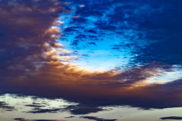 Vista sfocata di un vasto cielo blu pieno di nuvole scure gonfie al tramonto — Foto Stock