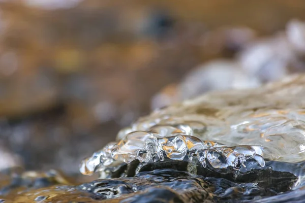 Primer plano de agua helada lisa y translúcida que cubre rocas oscuras —  Fotos de Stock