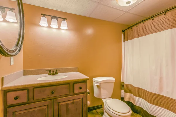 Toilettes et vanité avec armoire en bois et miroir rond à l'intérieur d'une salle de bain — Photo