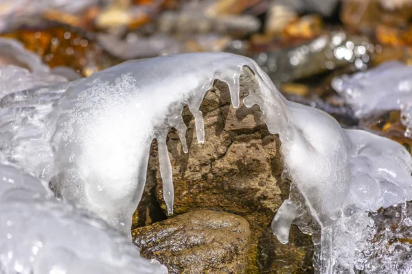 Nahaufnahme eines rauen und nassen braunen Felsens, der mit dickem weißen Eis bedeckt ist — Stockfoto