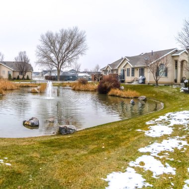 Kar ile yemyeşil çim çevrili merkezinde bir çeşme ile Kare Küçük gölet