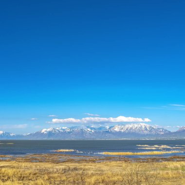 Çerçeve Kare Uzakta mavi gökyüzüne karşı karlı dağ ile bir gölün panoramik görünümü