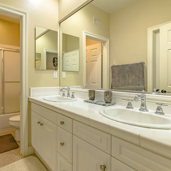 Quadratischer Innenraum eines kleinen Badezimmers mit Doppelwaschtisch und Holzschränken — Stockfoto
