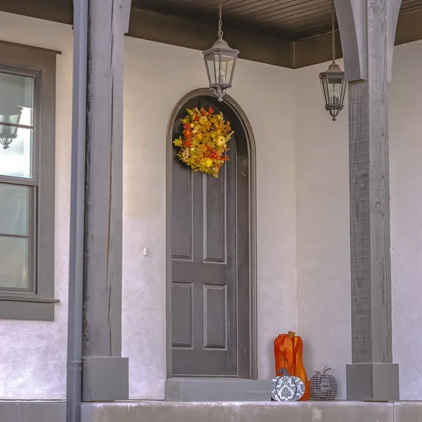 Fachada cuadrada de una casa con un pequeño porche delantero y puerta arqueada con corona — Foto de Stock