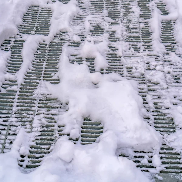 Frame Square Close up of a metal mesh drainage cover on a road covered with snow — Stock Photo, Image