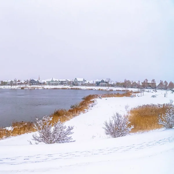 Cuadro Cuadrado Panorama de un lago plateado con costa cubierta de nieve y puente de metal — Foto de Stock