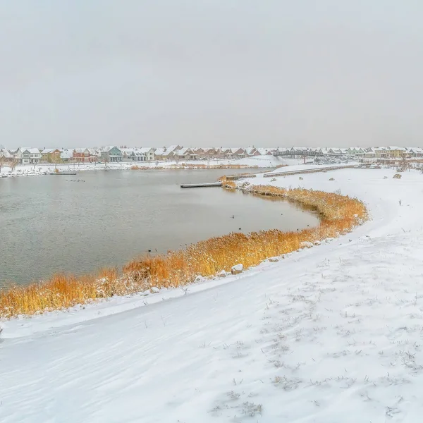 Sendero cubierto de nieve cuadrada con huellas a lo largo de un lago plateado en invierno — Foto de Stock