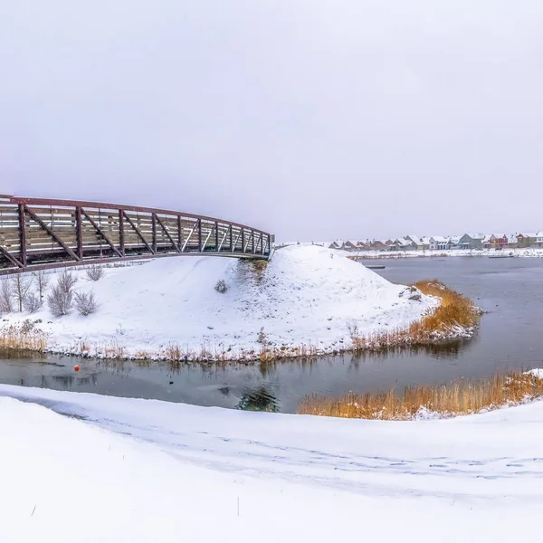 Piazza Panorama di un lago argentato con sponda innevata e ponte metallico — Foto Stock