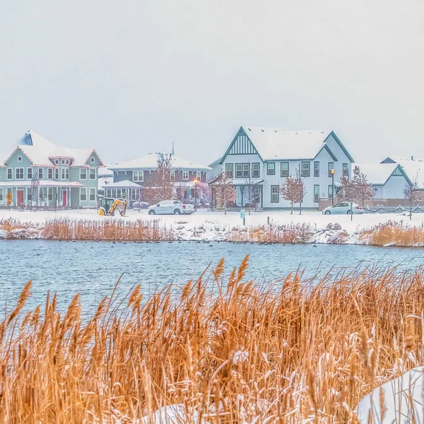 Plaza Hermoso lago ondulante con hierbas de color marrón amarillento en la orilla nevada — Foto de Stock