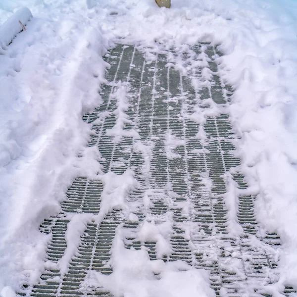 Square Close up of a metal mesh drainage cover on a road covered with snow — Stock Photo, Image