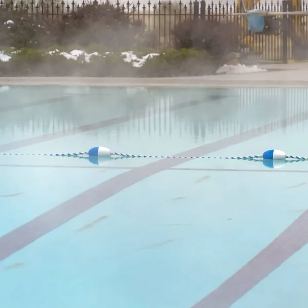 Bouée carrée bleue et blanche et marqueur de voie de corde flottant sur une piscine extérieure — Photo