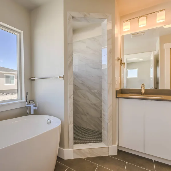 Interior do banheiro quadrado com banheira de vidro porta chuveiro e área de vaidade — Fotografia de Stock