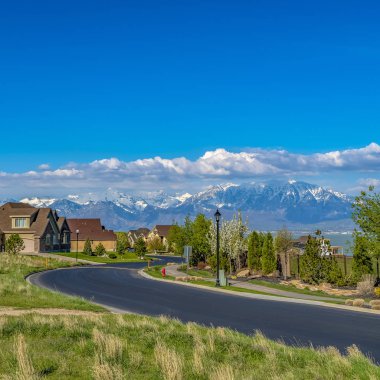 Güneşli bir günde göle bakan çimenli bir tepeüzerinde Square Curving yol ve evler
