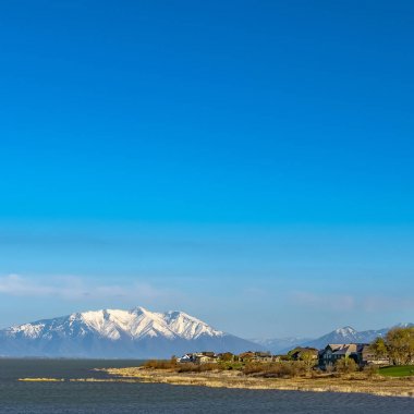 Çimenli kıyı ve dağ ve mavi gökyüzüne karşı pırıl pırıl su ile Kare Gölü