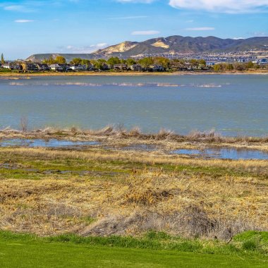 Kare Parlak yeşil çimenli alan mavi gökyüzü tepede yansıtan bir gölün önünde