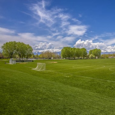 Bir çit arkasında futbol gol ağı ve beyzbol tribünleri ile Square Vast spor sahası