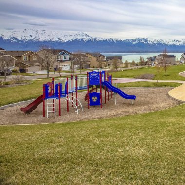 Square Park ve oyun alanı bir göl yakınında yemyeşil çim ve güzel evler ortasında